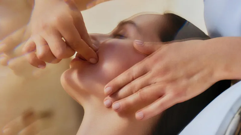 Tratamiento facial de Natura Bissé: unas manos masajean el rostro de una mujer con los ojos cerrados