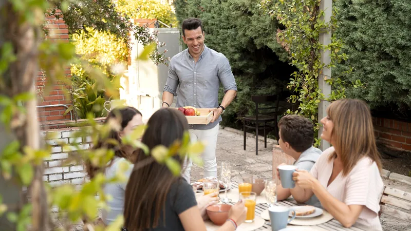 Familia de varias generaciones comiendo en una mesa larga en el jardín