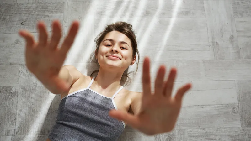 Mujer extiende las manos hacia la luz de la mañana junto a la ventana