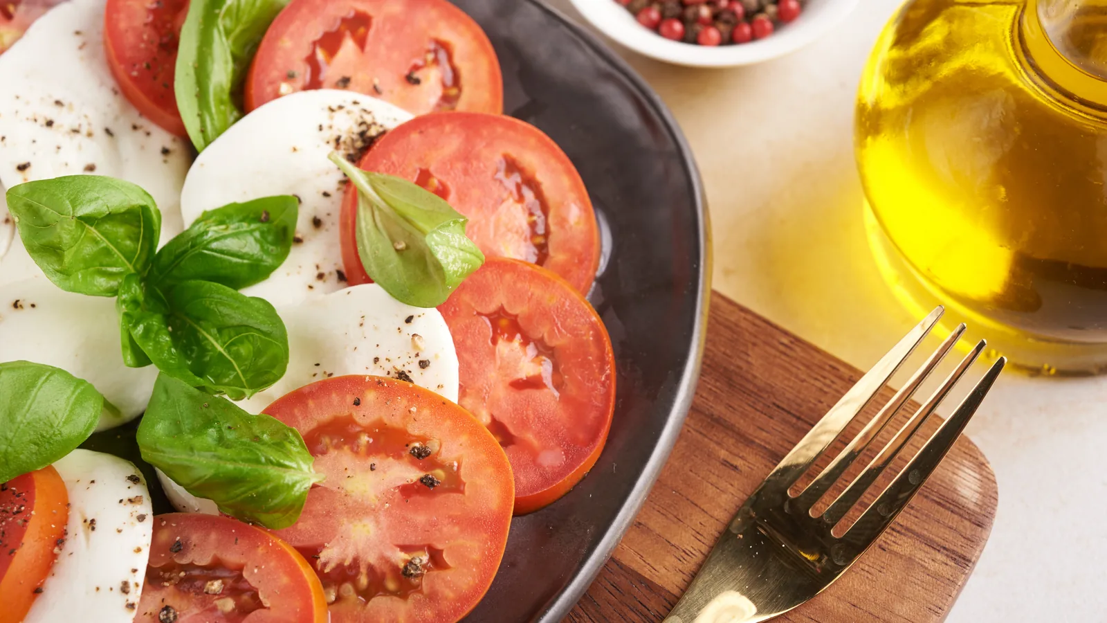Tomate, mozzarella y albahaca con aceite de oliva sobre una tabla de madera